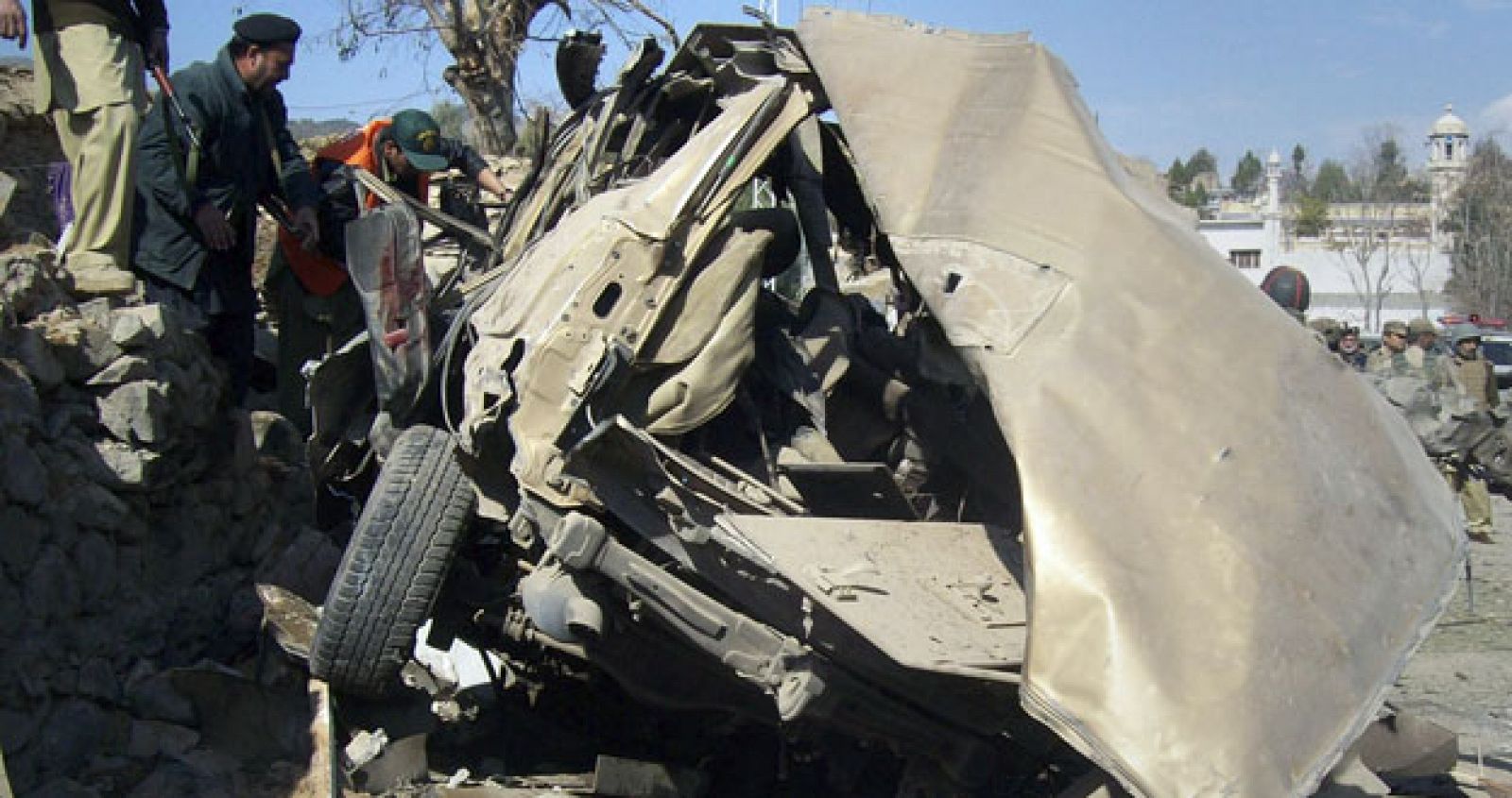 Police and rescue workers look into a destroyed vehicle at the site of a bombing which hit near a school in Timergara in Lower Dir Pakistan