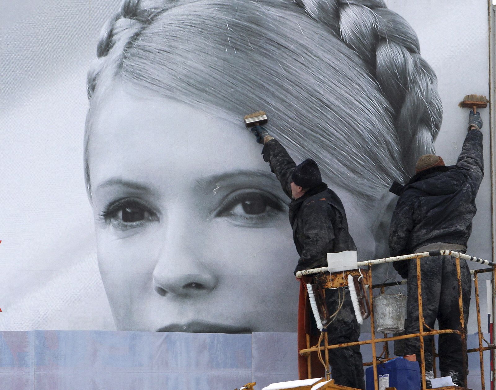 Un grupo de trabajadores municipales colocan un cartel electoral de la candidata Timoshenko.