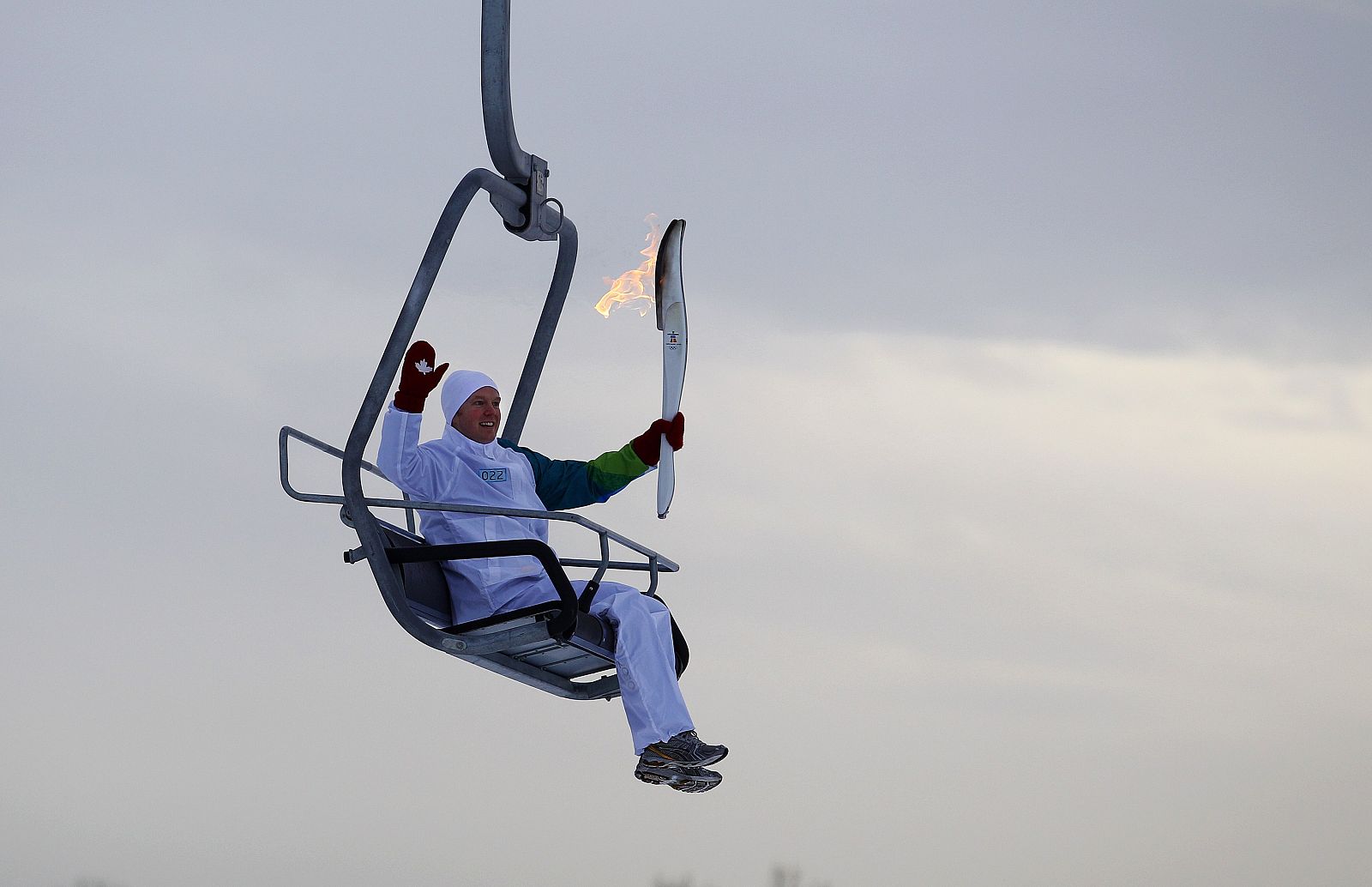 McDonough carries the Olympic Torch while riding a chairlift during the 2010 Winter Olympic Torch run at Canada Olympic Park in Calgary