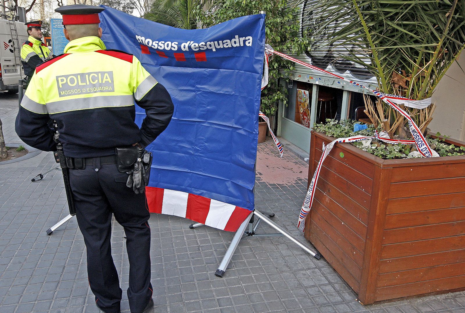 Dos Mossos d'Esquadra custodian la entrada del bar donde han sido hallados sin vida los cuerpos.