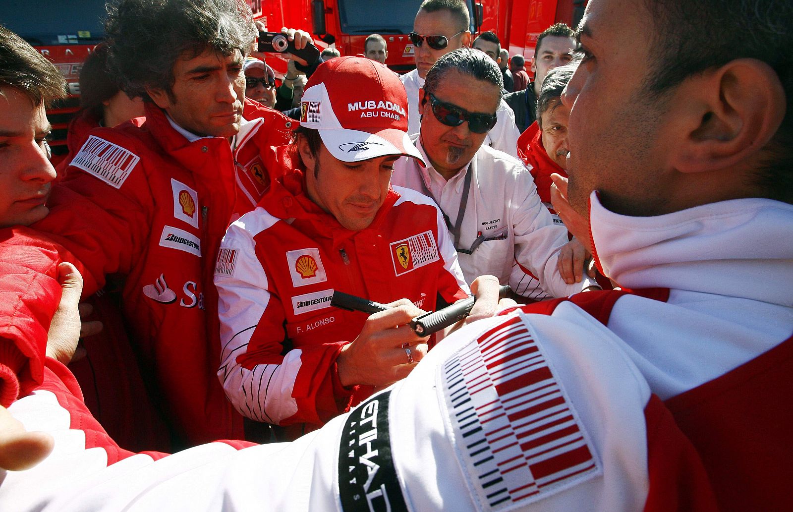 Fernando Alonso firma autógrafos rodeado de aficionados y periodistas en el circuito de Montmeló.