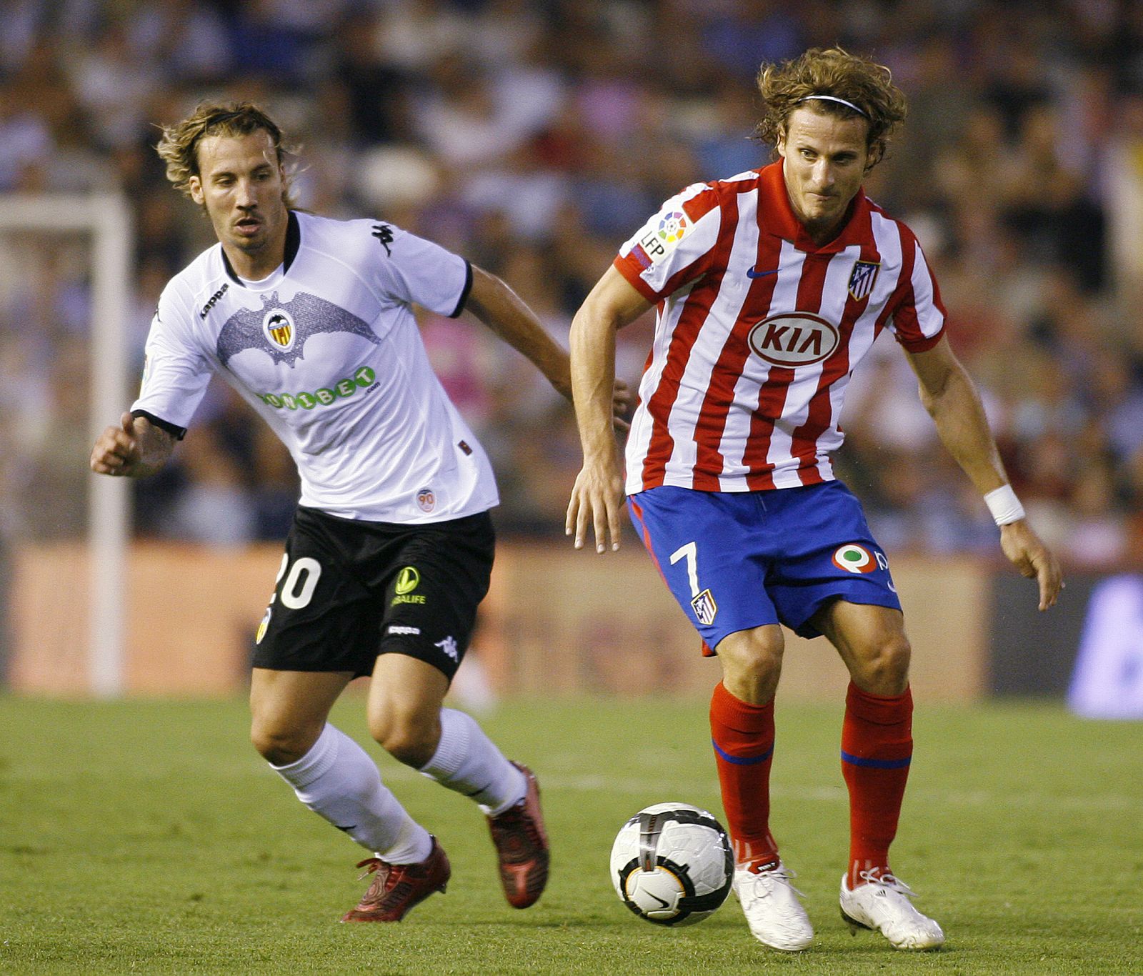 El jugador del Atlético de Madrid, Diego Forlan, y el valencianista Alexis Ruano luchan por el control de la pelota.