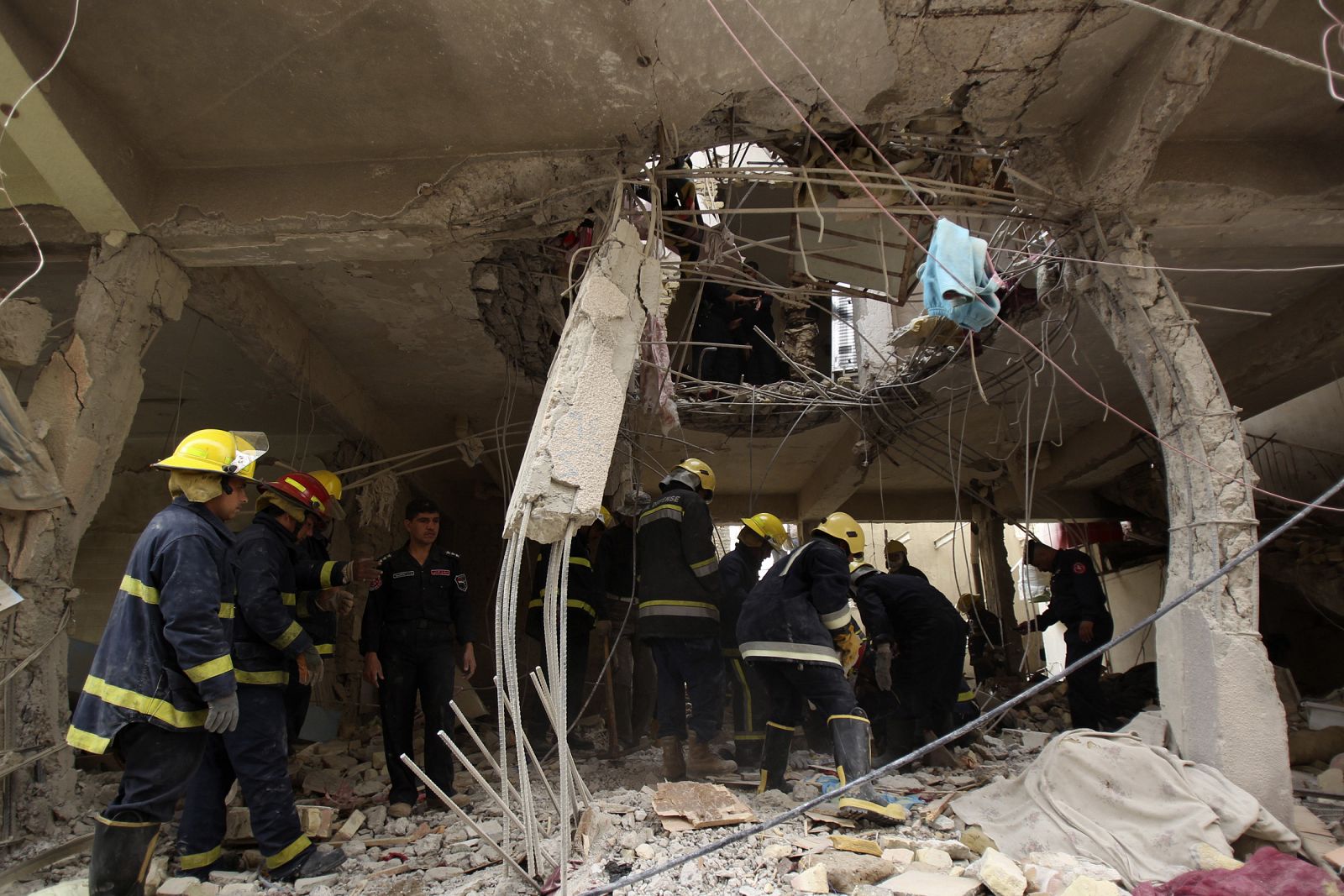 Iraqi civil defence members inspect a damaged building after a bomb attack in Baghdad