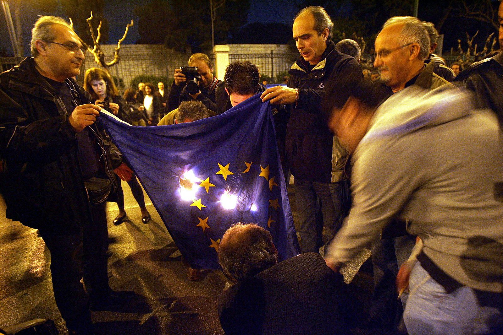 Varios manifestantes queman una bandera de la Unión Europea esta madrugada en Atenas.