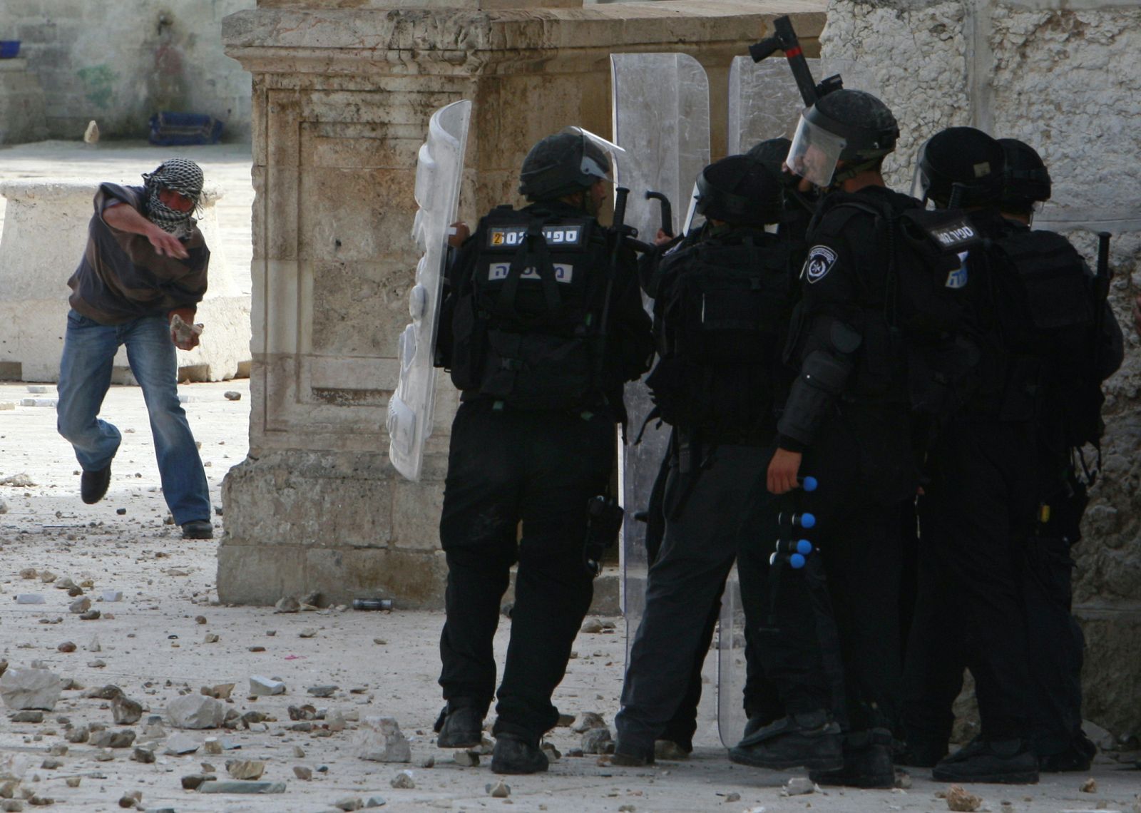 A Palestinian throws a stone at Israeli police during clashes in Jerusalem's Old City