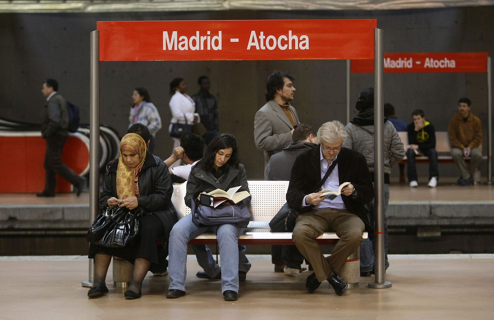 Varias personas esperan un tren de Cercanías en la estación de Atocha