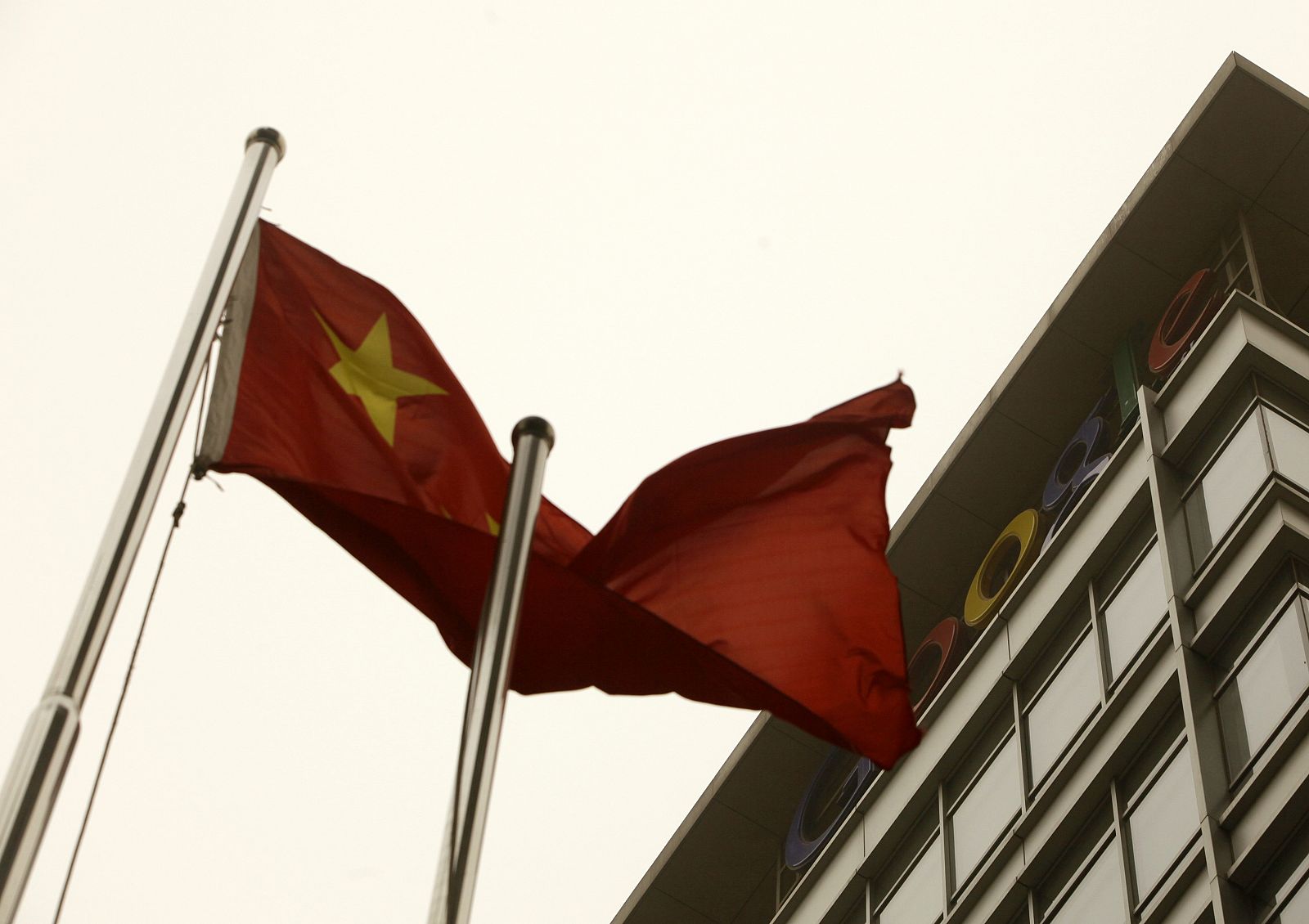 A Chinese national flag waves in front of the Google logo in Beijing