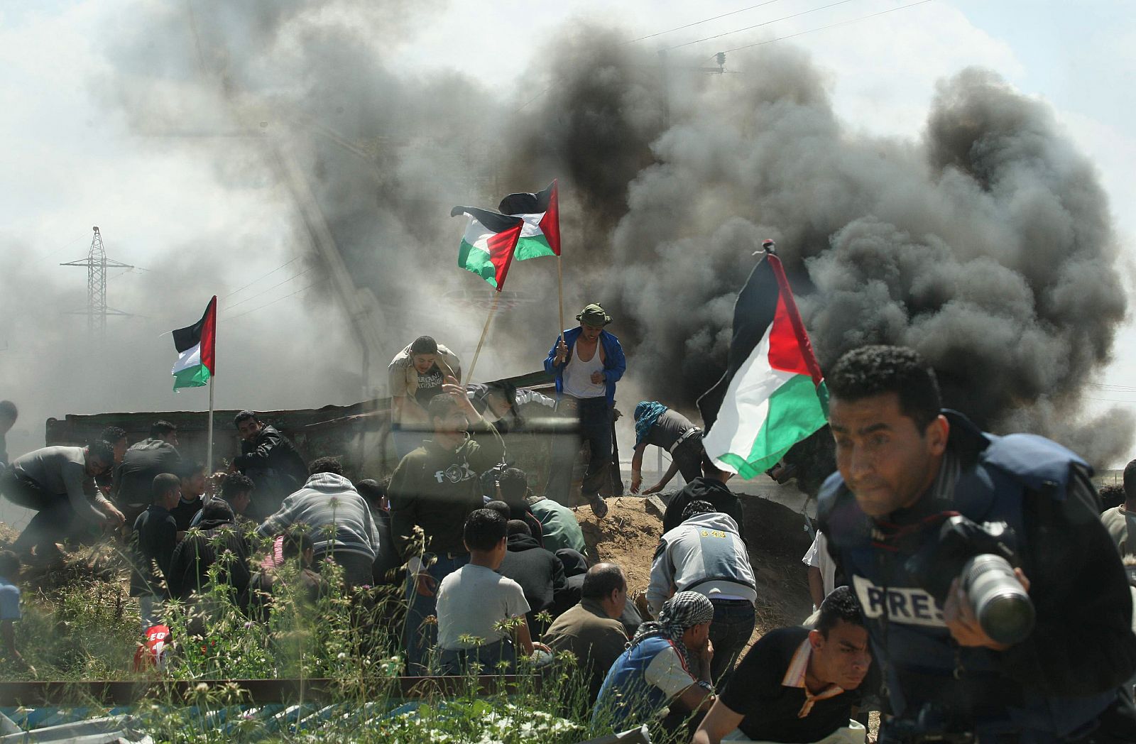 Manifestantes palestinos se cubren de los disparos israelíes en Gaza.
