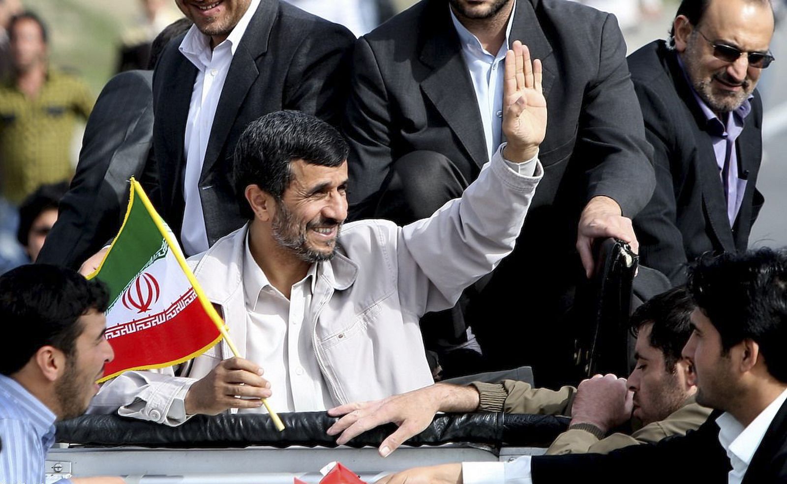 El presidente iraní Ahmadineyad sostiene una bandera mientras saluda a una multitud en un viaje a la pronvia de Orumieh.