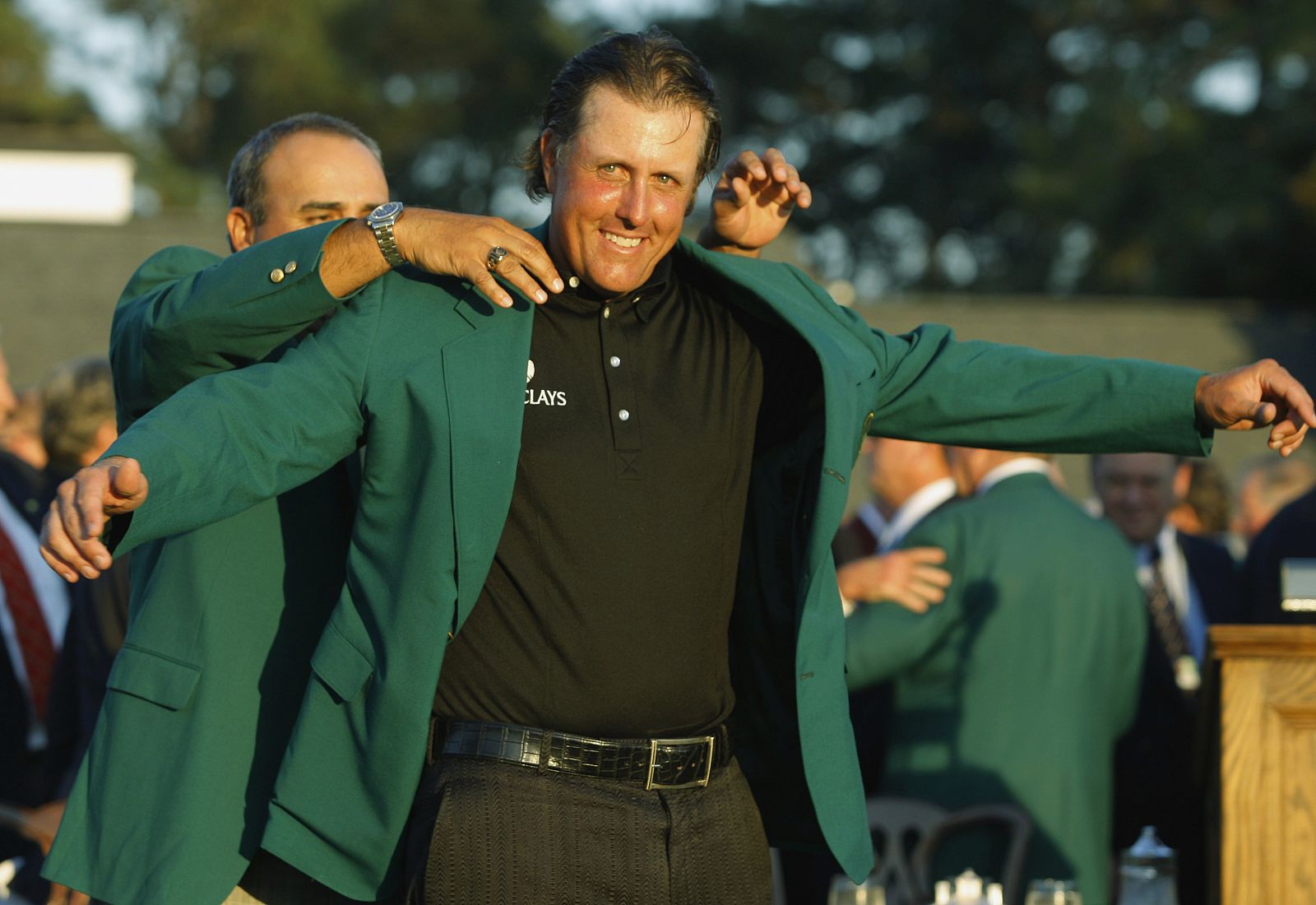 Phil Mickelson es ayudado para ponerse la chaqueta verde que le acredita como ganador del Masters de Augusta.