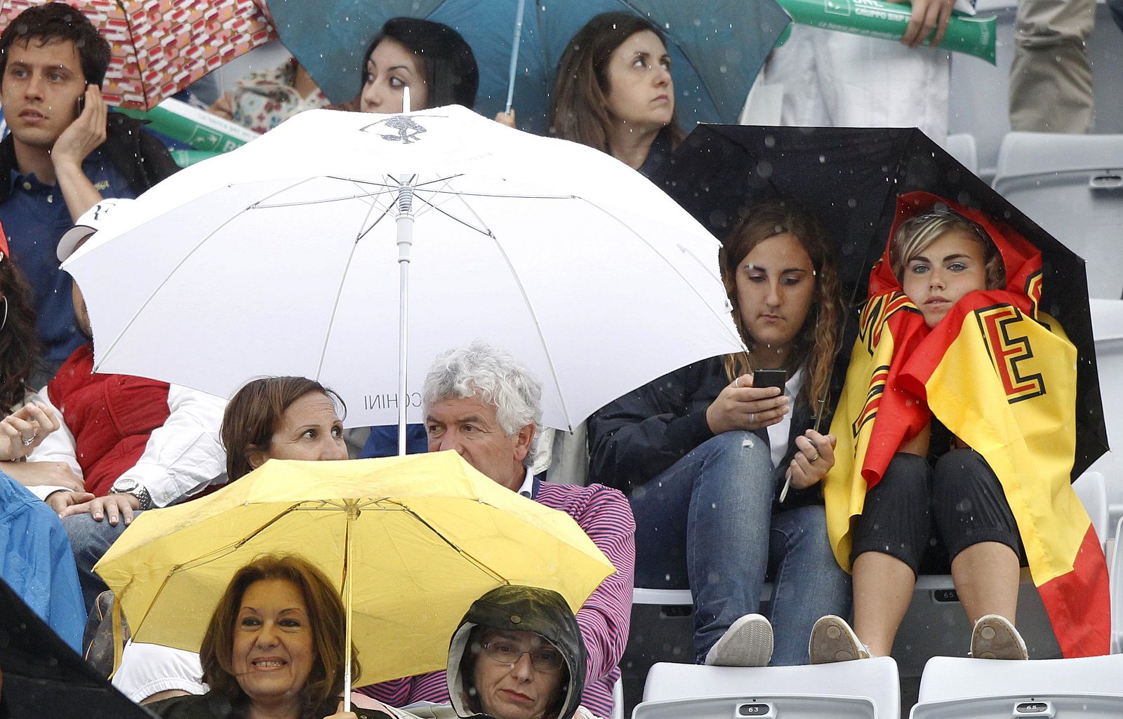 Los espectadores de la final, protegiéndose bajo la lluvia.