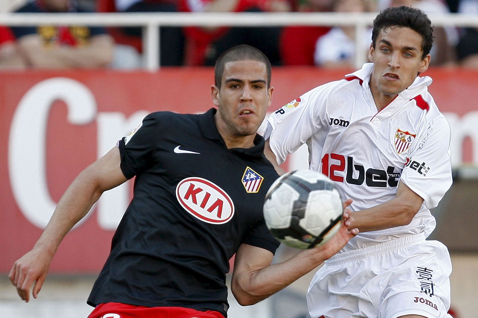 El centrocampista del Sevilla FC Jesús Navas presiona al defensa del Atlético de Madrid, Álvaro Domínguez.