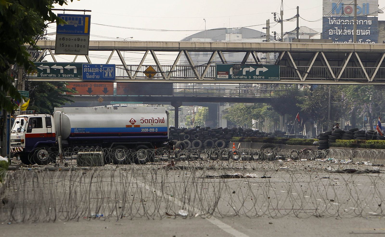 Un manifestante, a la derecha, dispara al ejército desde una barricada de neumáticos de los "camisas rojas" en Rama IV Street, en Bangkok.