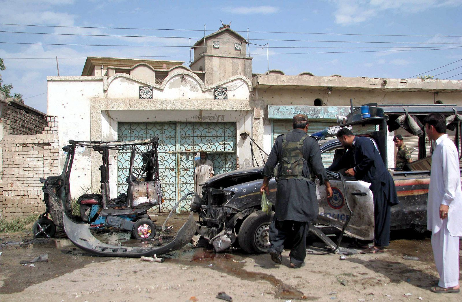Agentes paquistaníes inspeccionan un coche de la Policía dañado en la explosión de una bomba