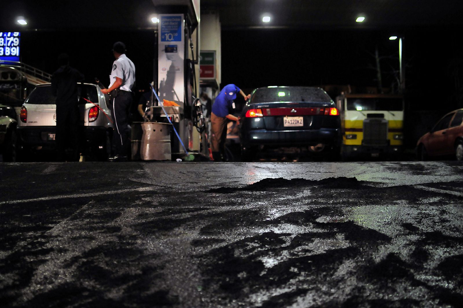 Varias personas permancen en una gasolinera cubierta con ceniza volcánica