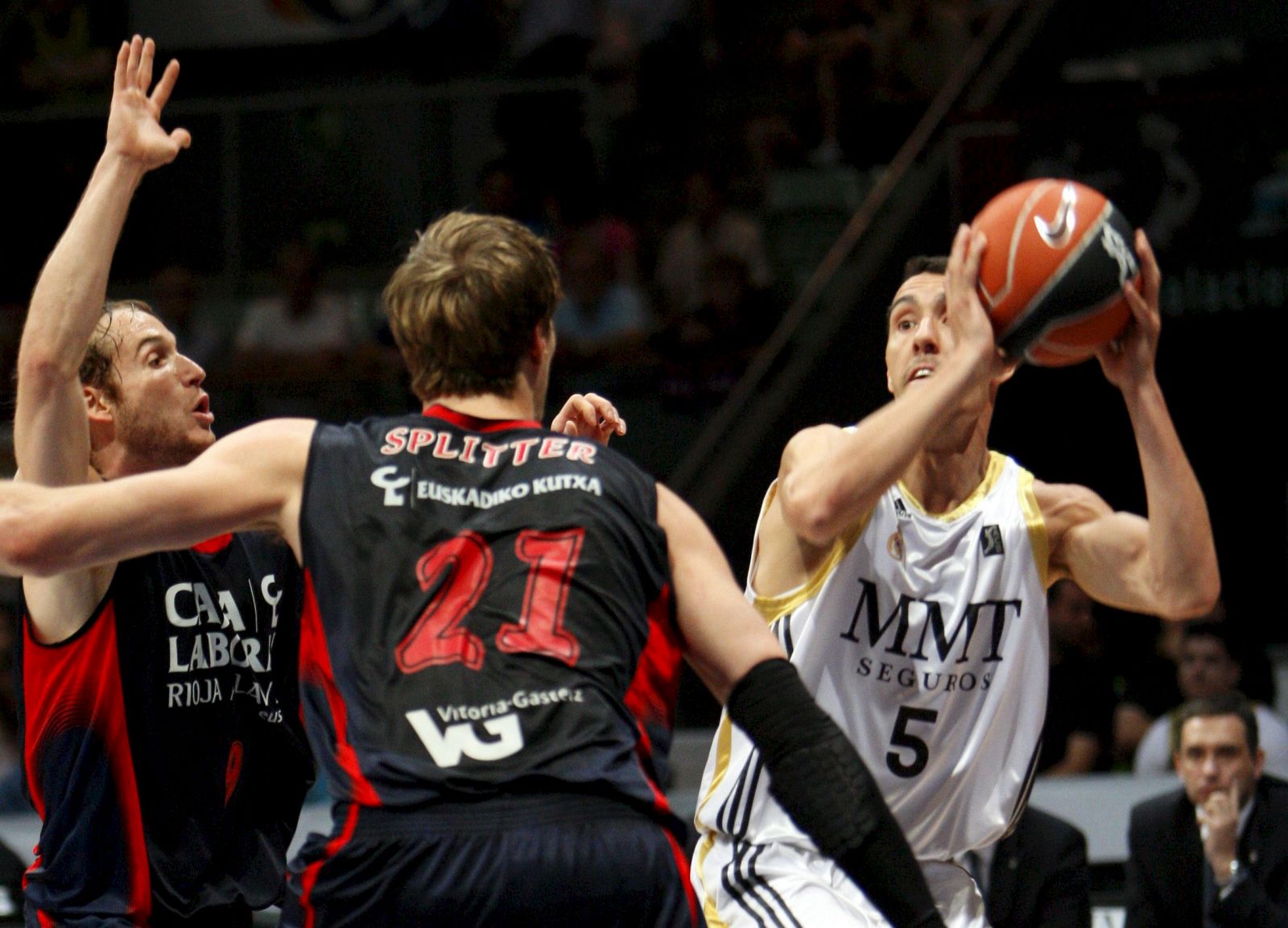 El base argentino del Real Madrid, Pablo Prigioni, intenta eludir la defensa de los jugadores brasileños del Caja Laboral, Tiago Splitter y Marcelinho Huertas.