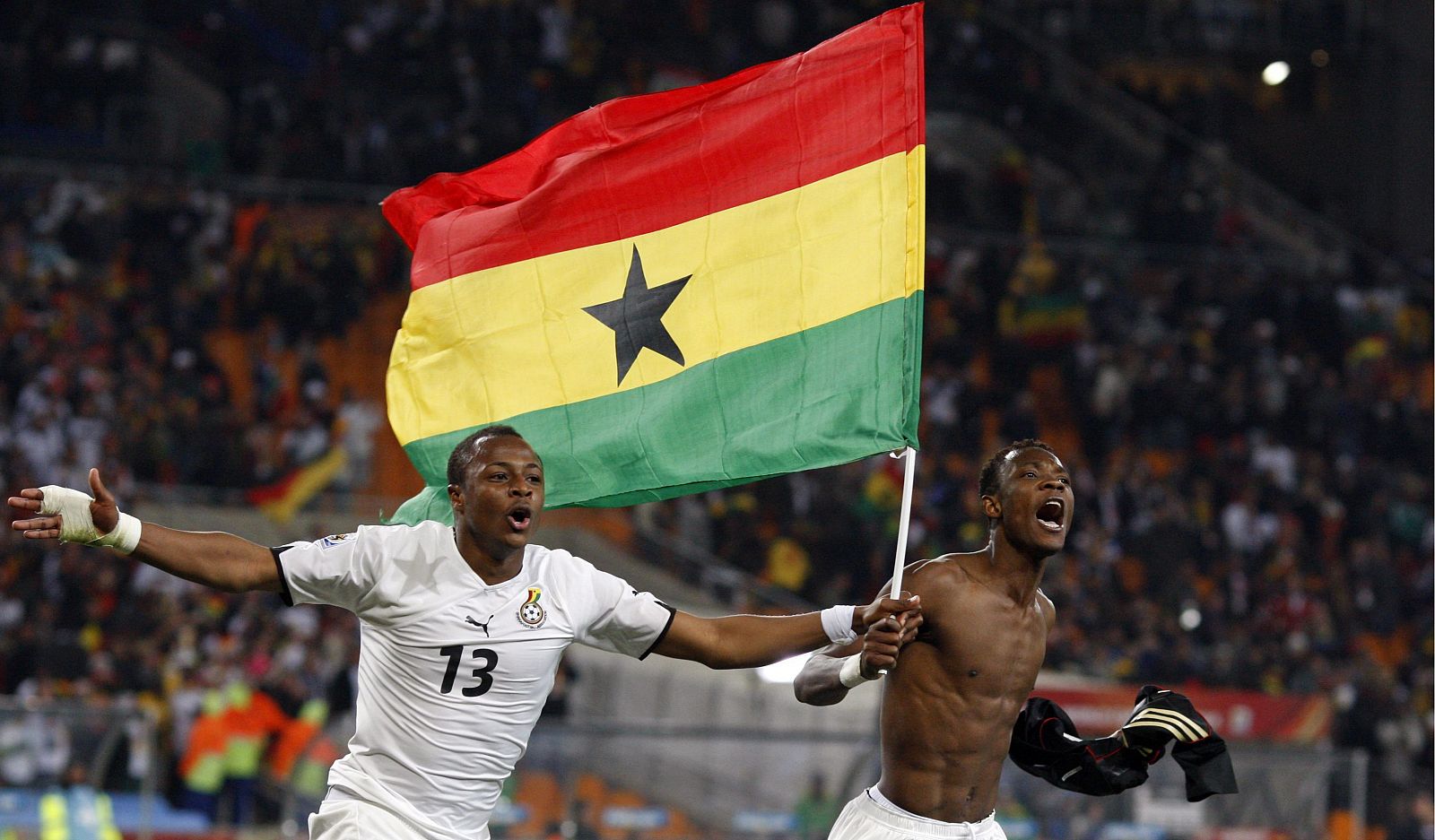 Los jugadores ghaneses Andre Ayew y John Pantsil celebran con una bandera nacional el pase de su selección a octavos.