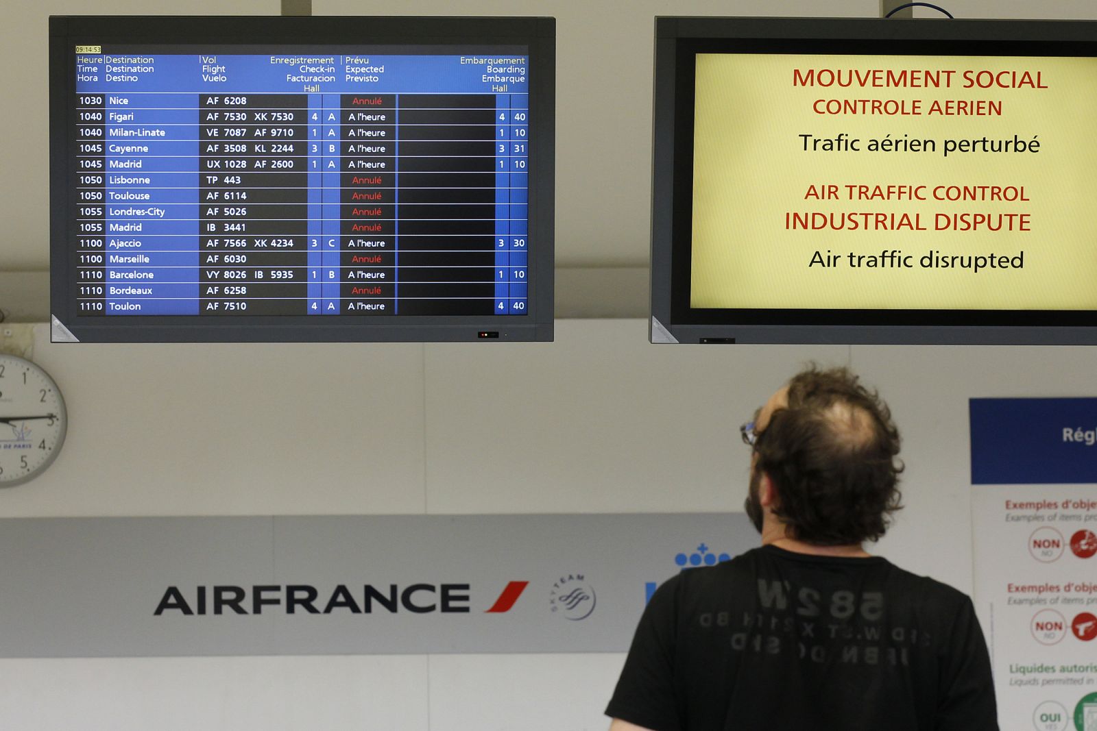 A passenger looks at flight information monitor at Orly airport near Paris after several flights were cancelled due to a strike by French air traffic controllers