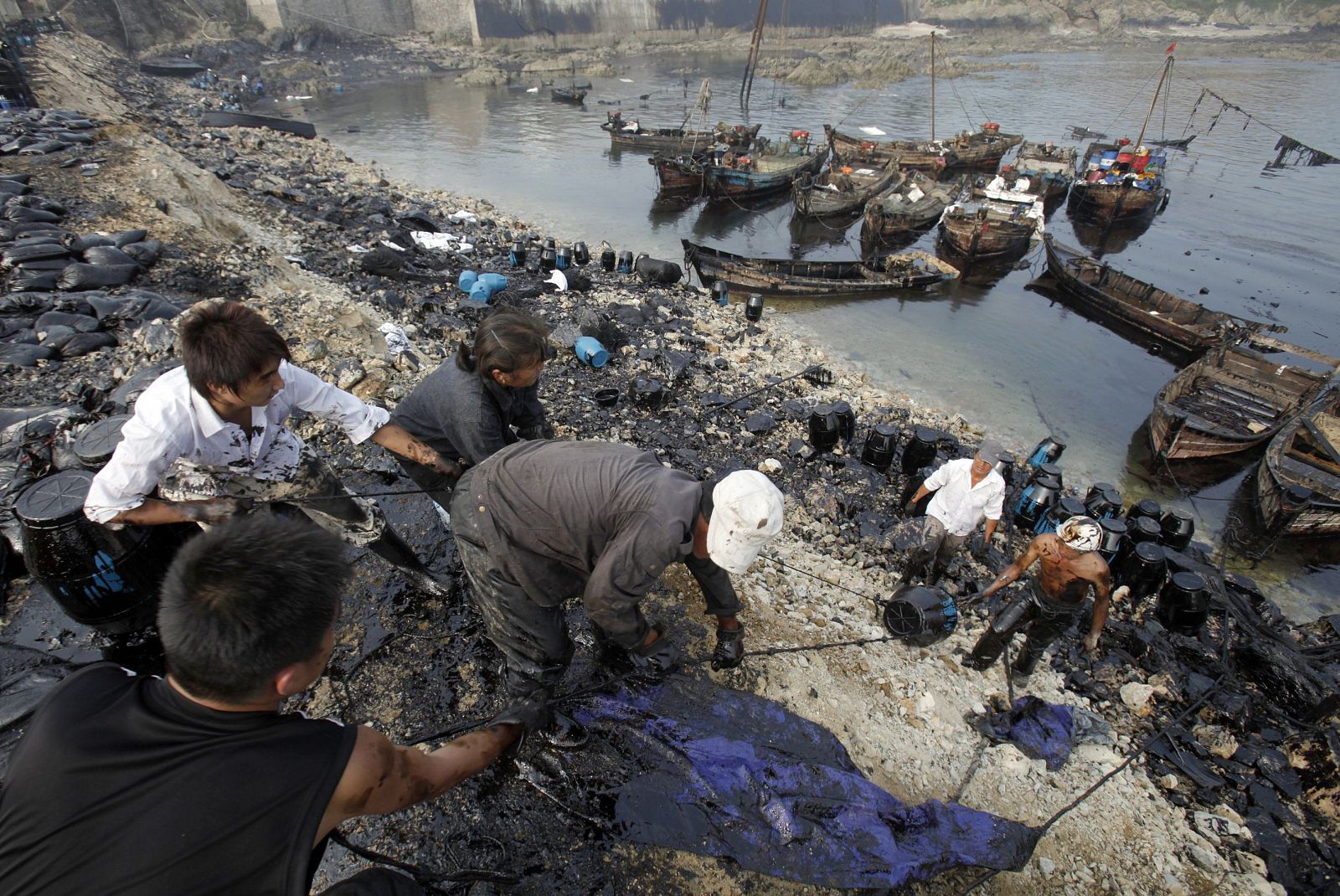 Local fishermen clean up oil near the oil spill site in Dalian