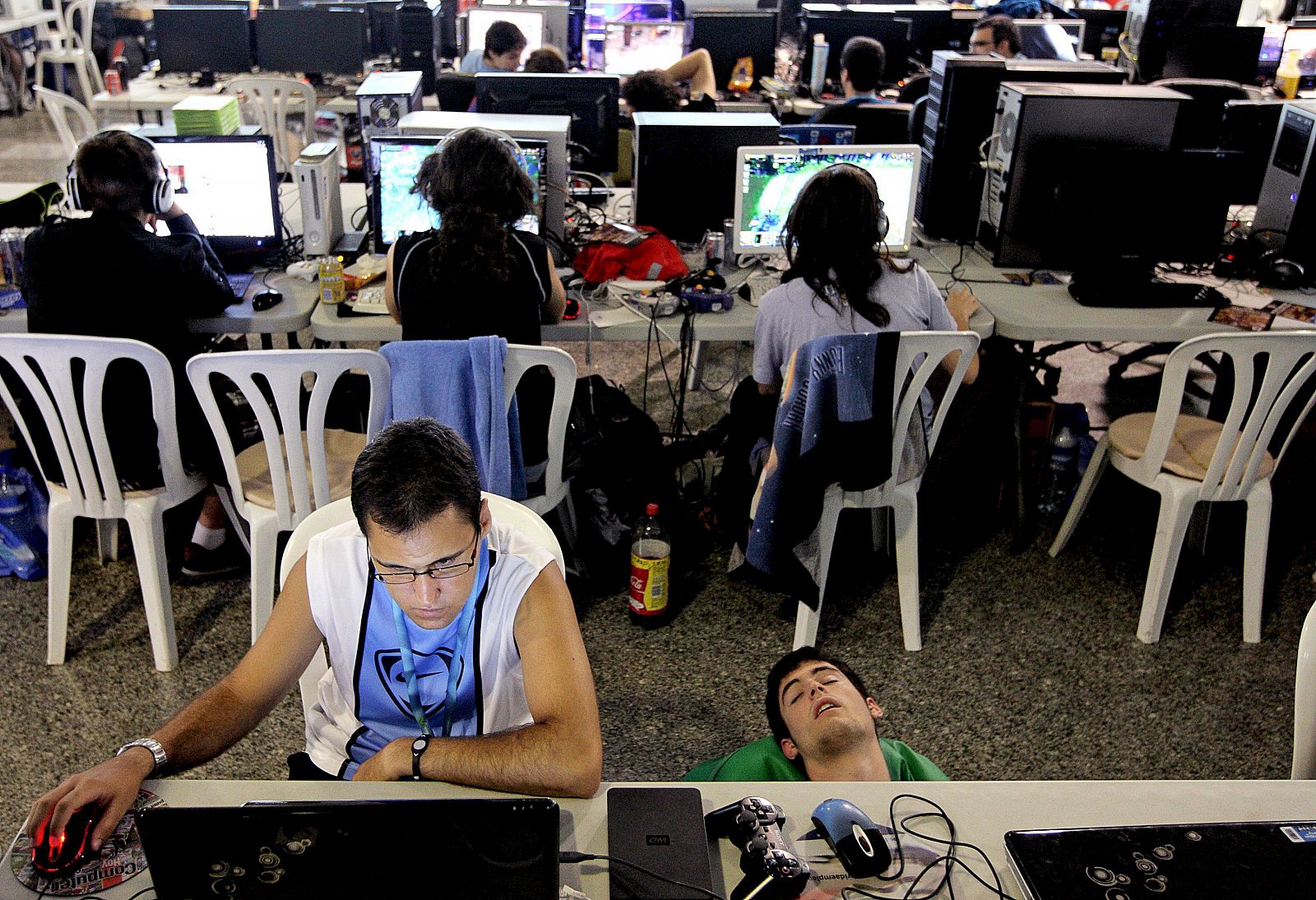 Uno de los campuseros duerme ante su ordenador junto a un compañero que continúa trabajando.