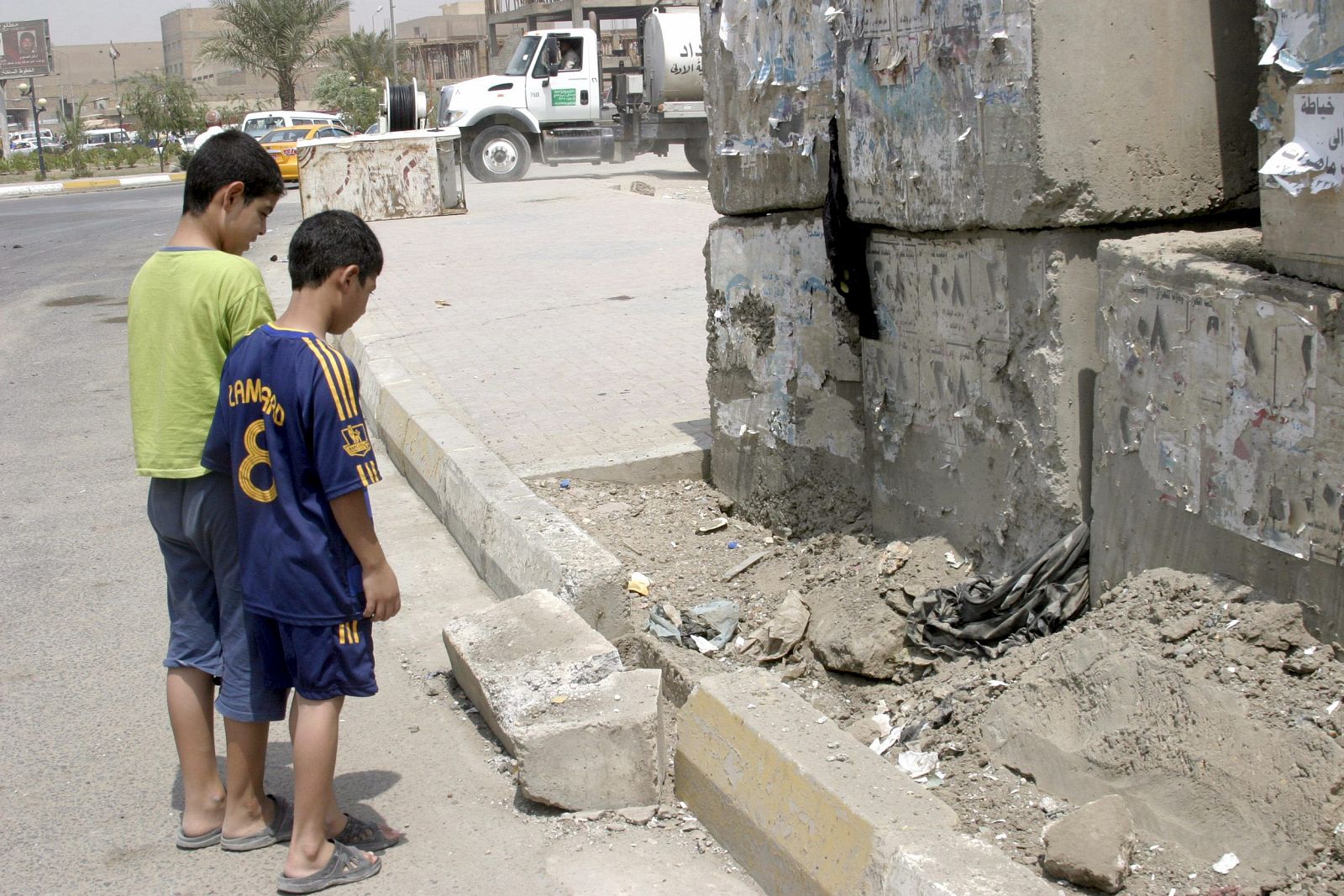 Dos muchachos iraquíes observan el daño causado a una acera por una bomba en Bagdad
