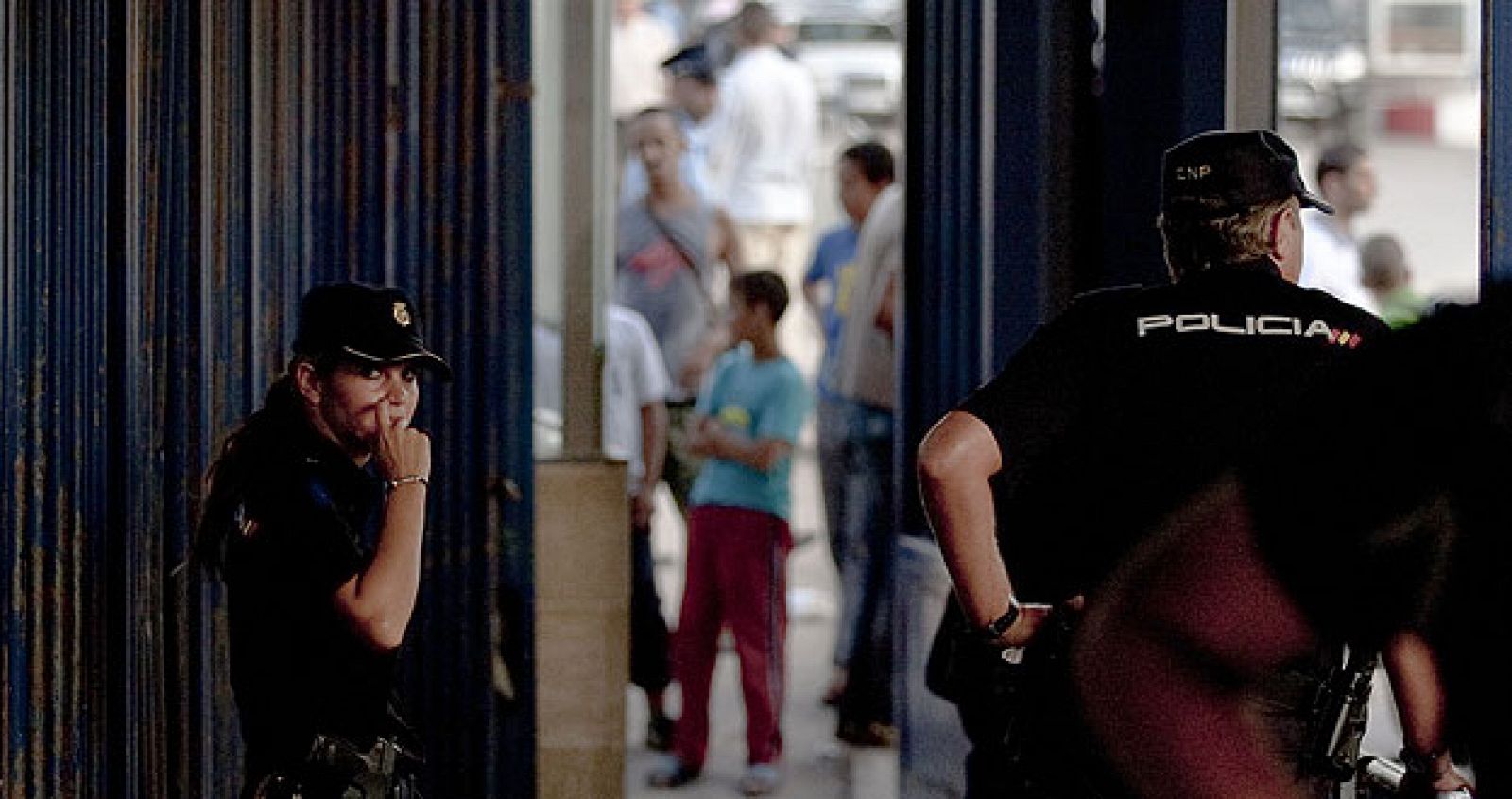 Dos agentes del cuerpo de la Policía Nacional observan desde el puesto fronterizo español el tránsito de vehículos y personas entre las fronteras de España y Marruecos.