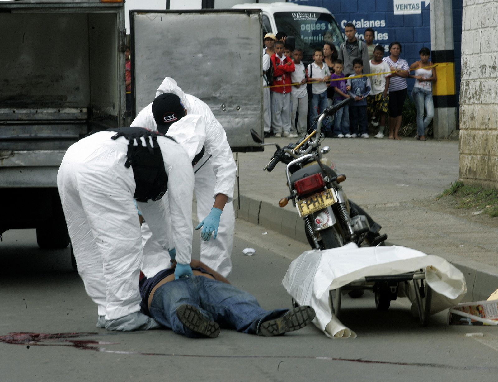 Coroners examine the body of a man killed by gunmen in downtown Medellin