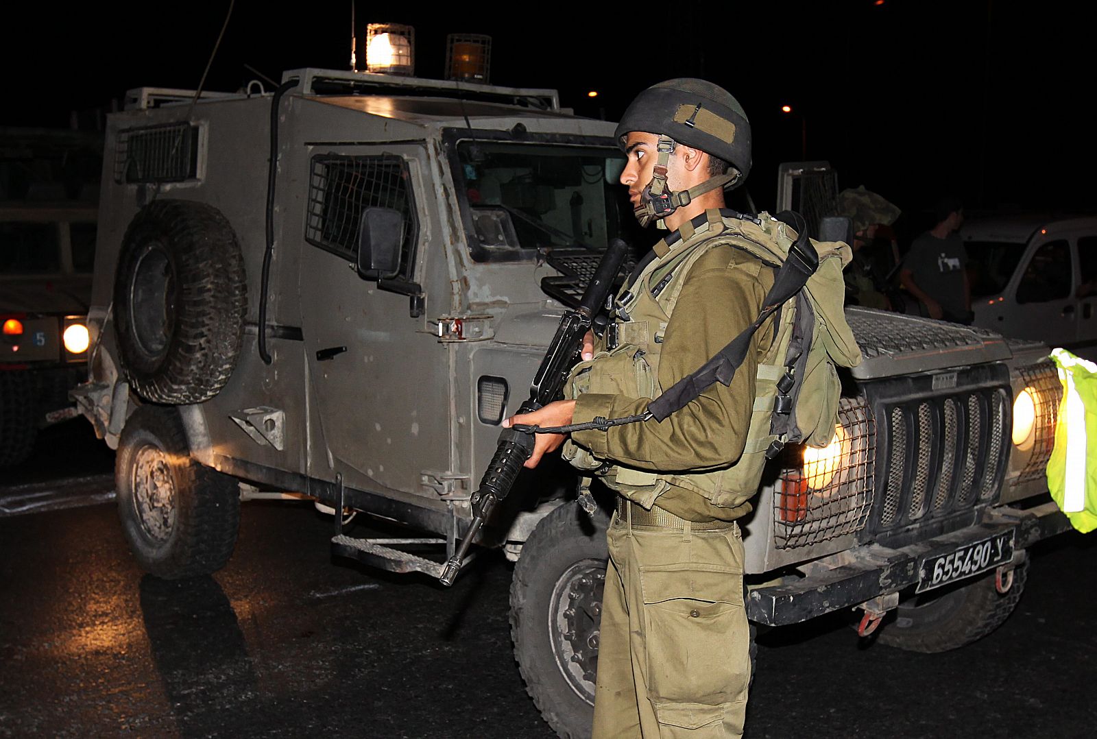 Un soldado israelí monta guardia cerca a un coche tiroteado a las afueras del asentamiento judío de Kiryat Arab en Cisjornadia donde han sido asesinados cuatro colonos.