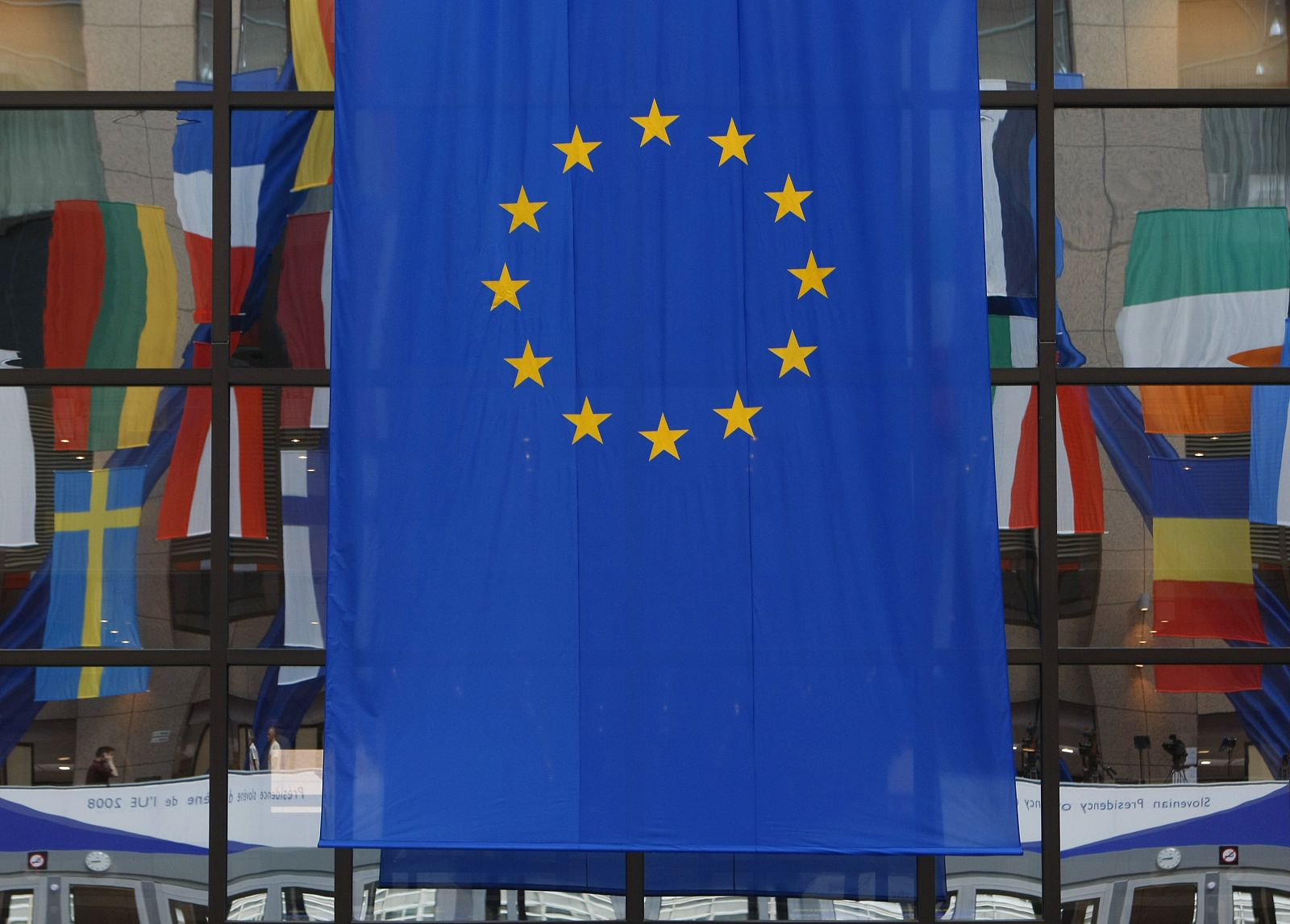 Flags are reflected in a window at the European Council building in Brussels
