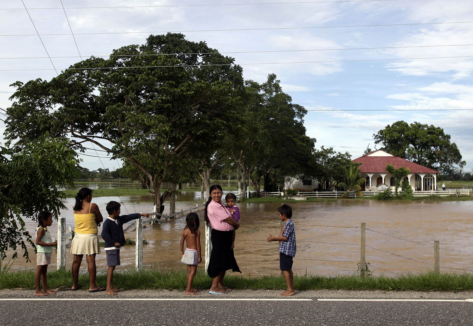 A family stops to watch as farmlands flood near Rio Dulce