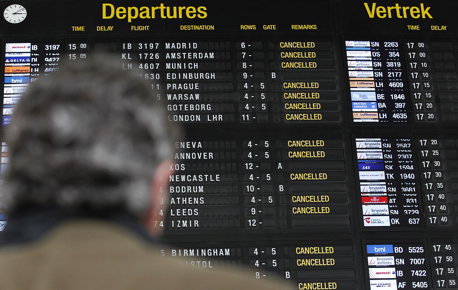 A stranded passenger waits under an information board during a strike at the Zaventem international airport near Brussels