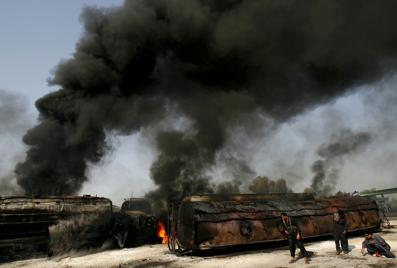La Policía recoge casquillos de bala junto a los camiones de la OTAN quemados en Shikarpur.