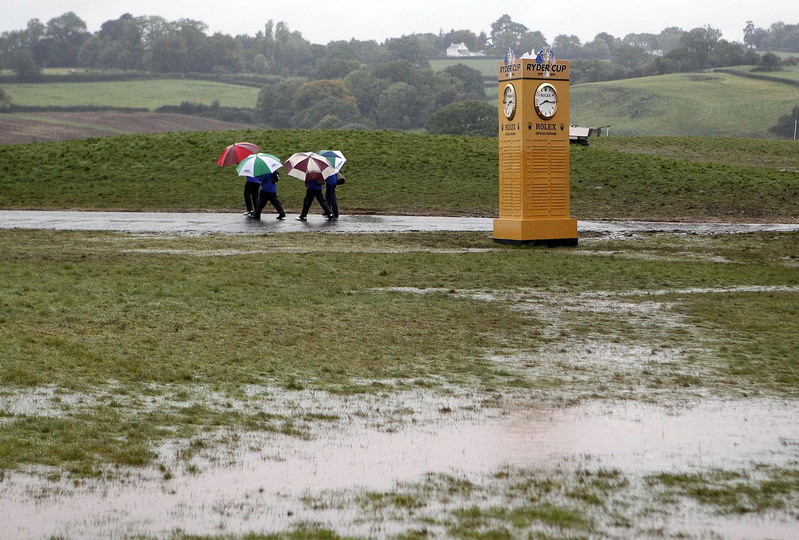 Unos comisarios de la Ryder Cup cruzan el campo inundado por la lluvia en Celtic Manor, al sur de Gales.