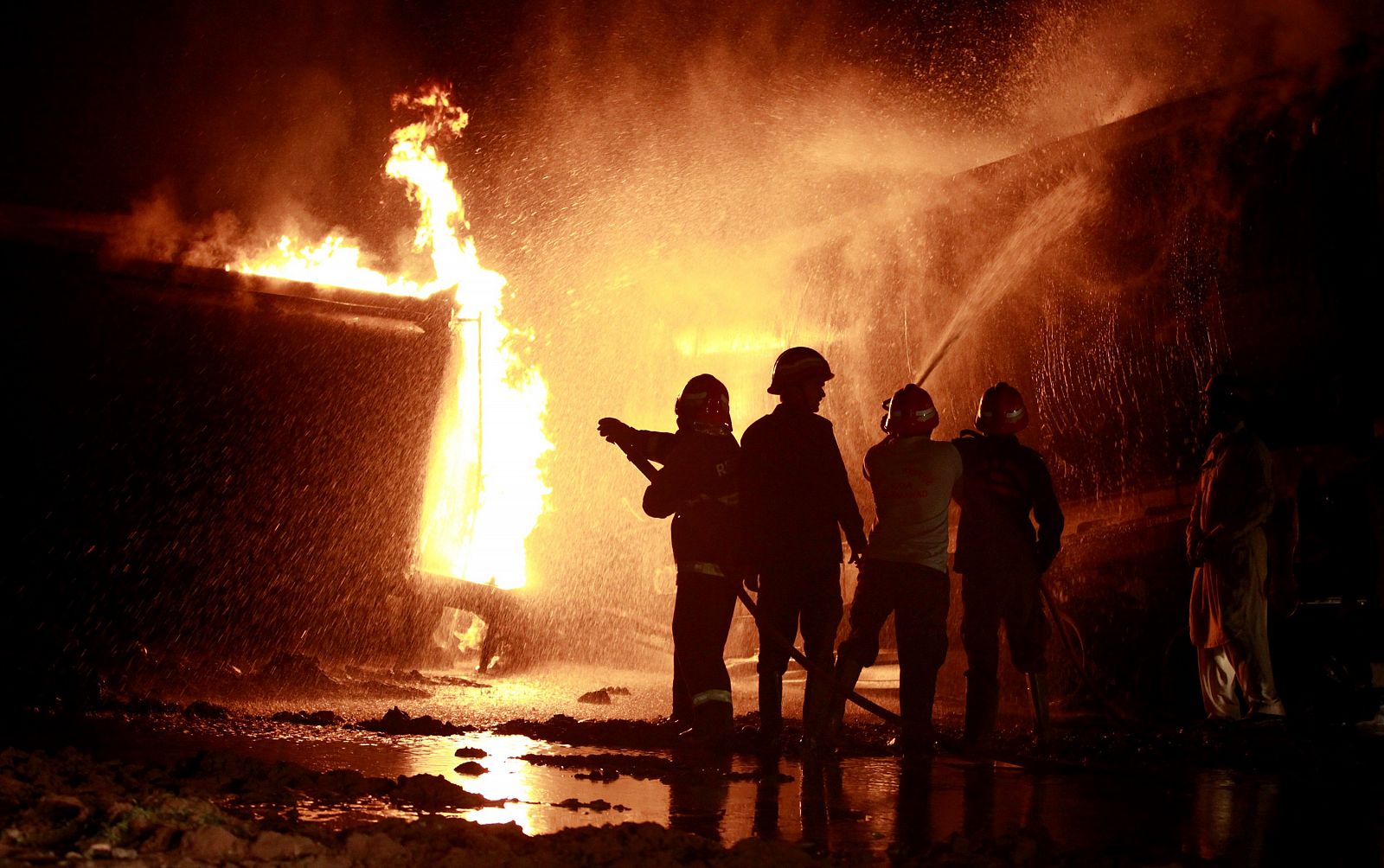 Los bomberos tratan de extinguir el fuego en los camiones cisterna de suministro de la OTAN tras el ataque registrado esta madrugada.