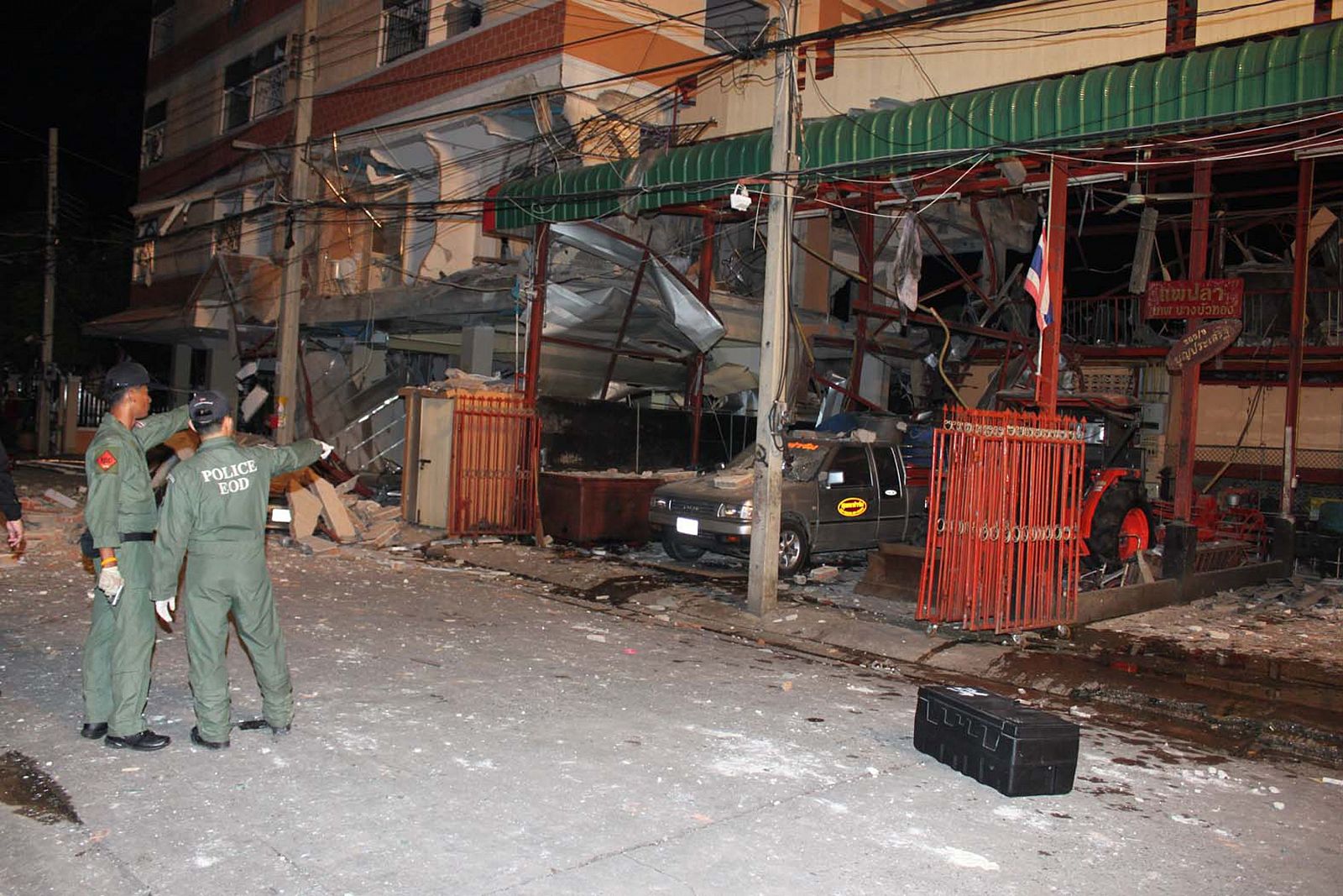 Miembros de seguridad tailandeses inspeccionan el lugar del atentado en un barrio de Bangkok.