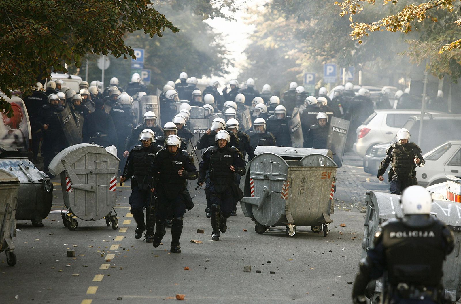 Riot policemen run down a street during clashes in Belgrade