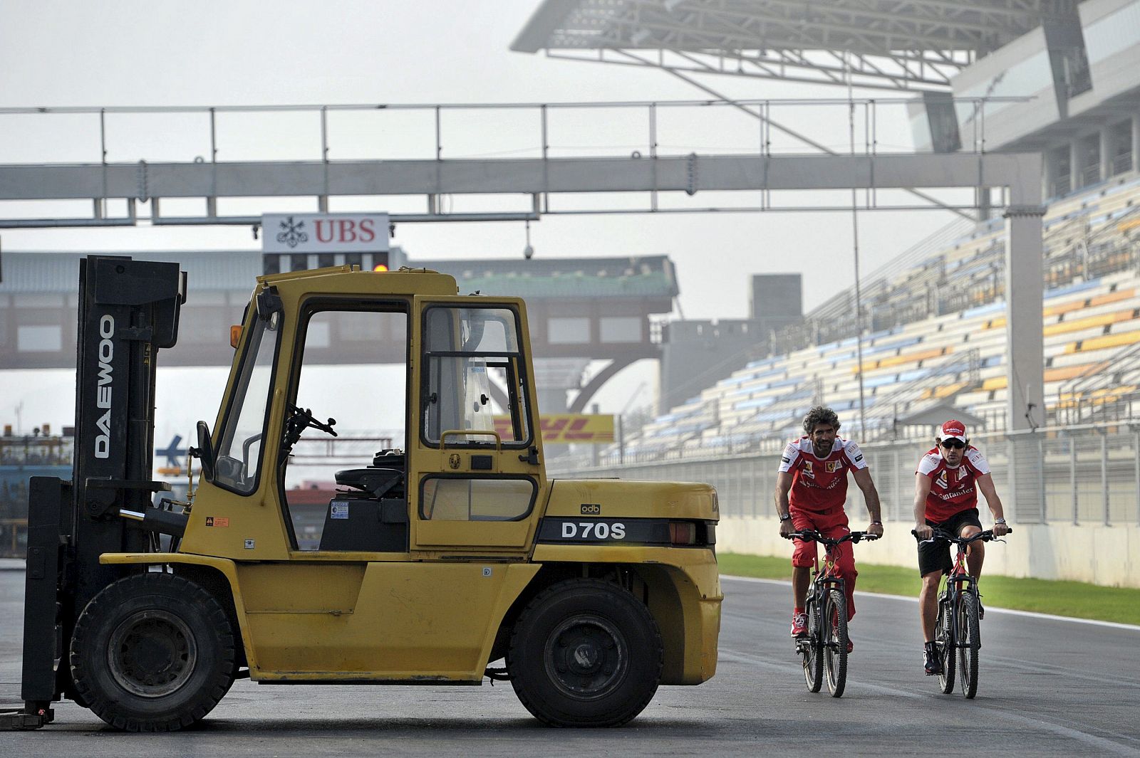 Fernando Alonso, de Ferrari, y un miembro de su equipo revisan en bici el Circuito de Corea.