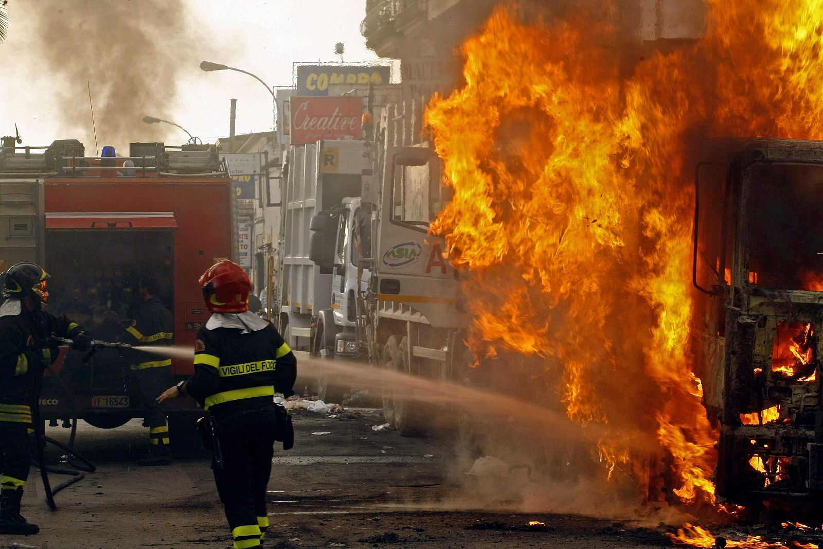 Los bomberos tratan de extinguir el fuego de los camiones incendiados por los manifestantes que protestan por la apertura de un nuevo vertedero en Terzigno, en Italia.