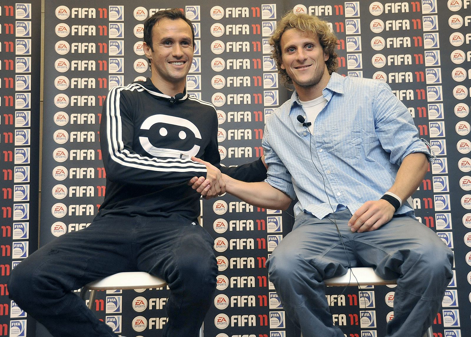 El defensa del Madrid, Carvalho, y el delantero del Atlético de Madrid, Forlán, se dan la mano en la presentación de un juego virtual.