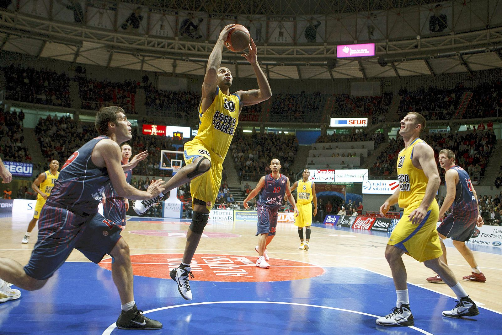 Ronald Burrell (2i), del Asecco Prokomn Gdynia, salta a canasta ante la mirada del escolta Fernando San Emeterio (i),