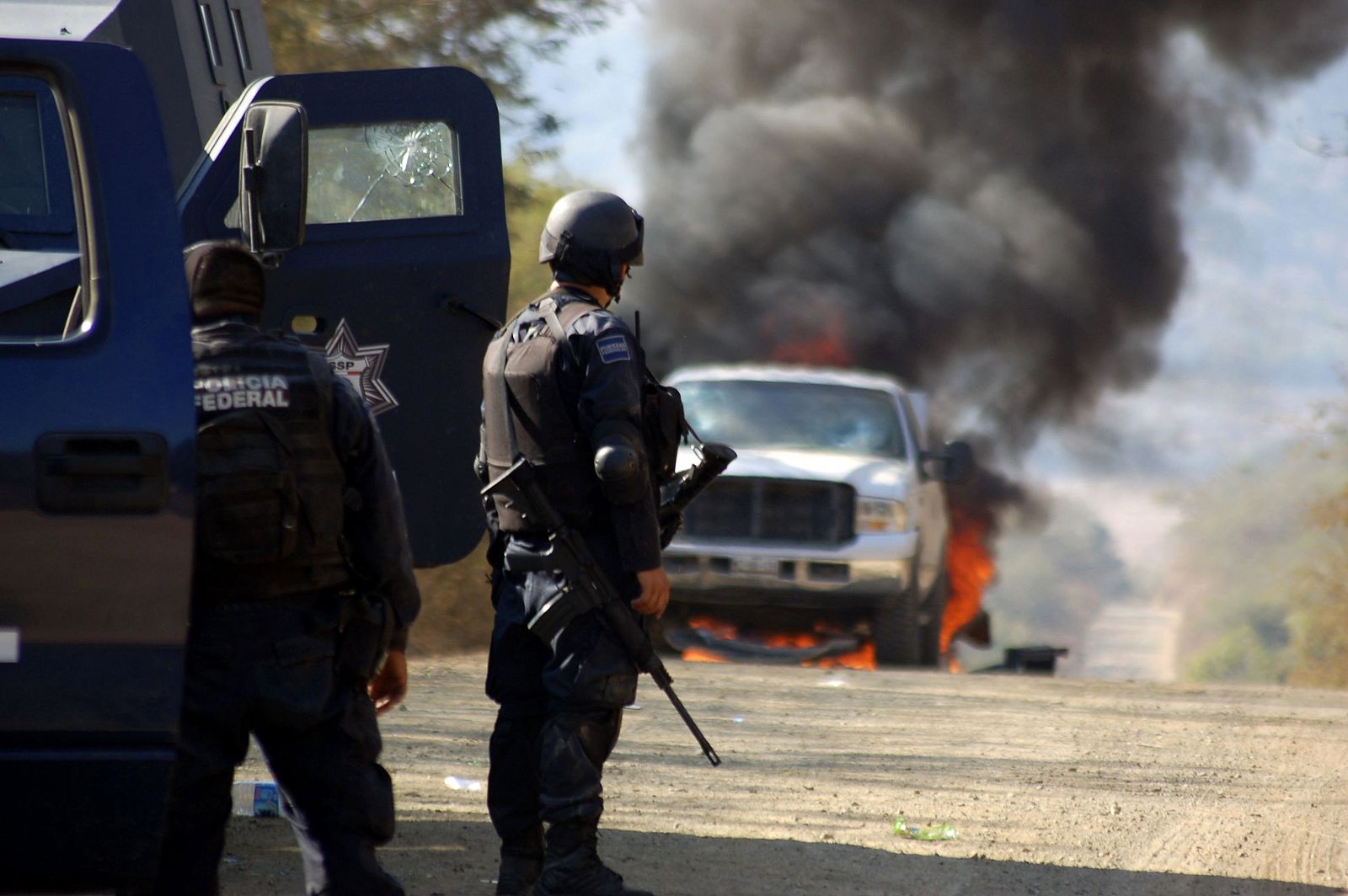 Policías observan cómo arde el coche de unos sospechosos durante la operación contra La Familia en las afueras de Apatzingán.