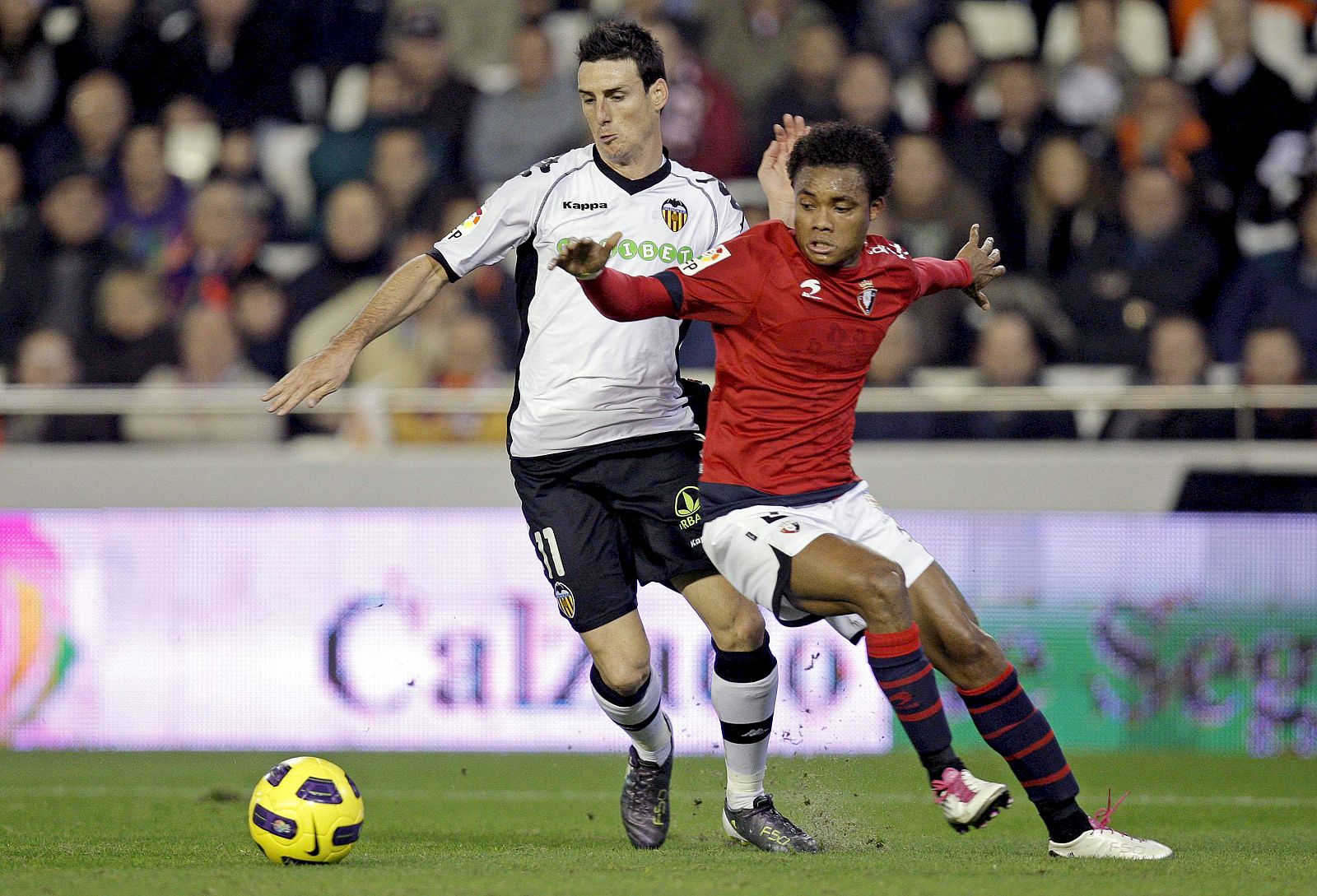 El delantero del Valencia Aritz Aduriz lucha un balón con el defensa portugués del Osasuna Nelson durante el partido correspondiente a la decimoquinta jornada de Liga disputado esta noche en el estadio de Mestalla.