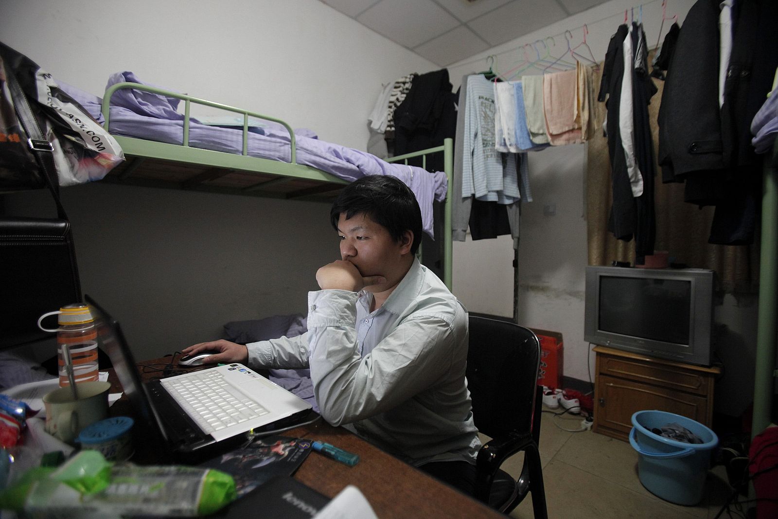 Un joven chino mira su portátil en una residencia de estudiantes en Shanghái.