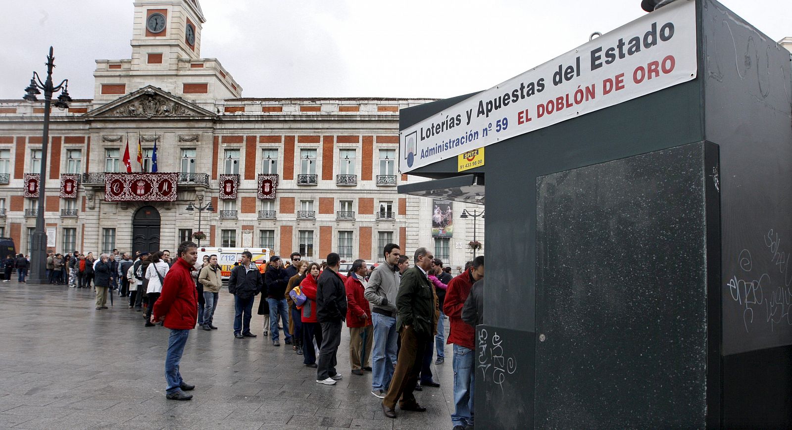 Numerosas personas guardan cola ante un quiosco de lotería en plena Puerta del Sol de Madrid