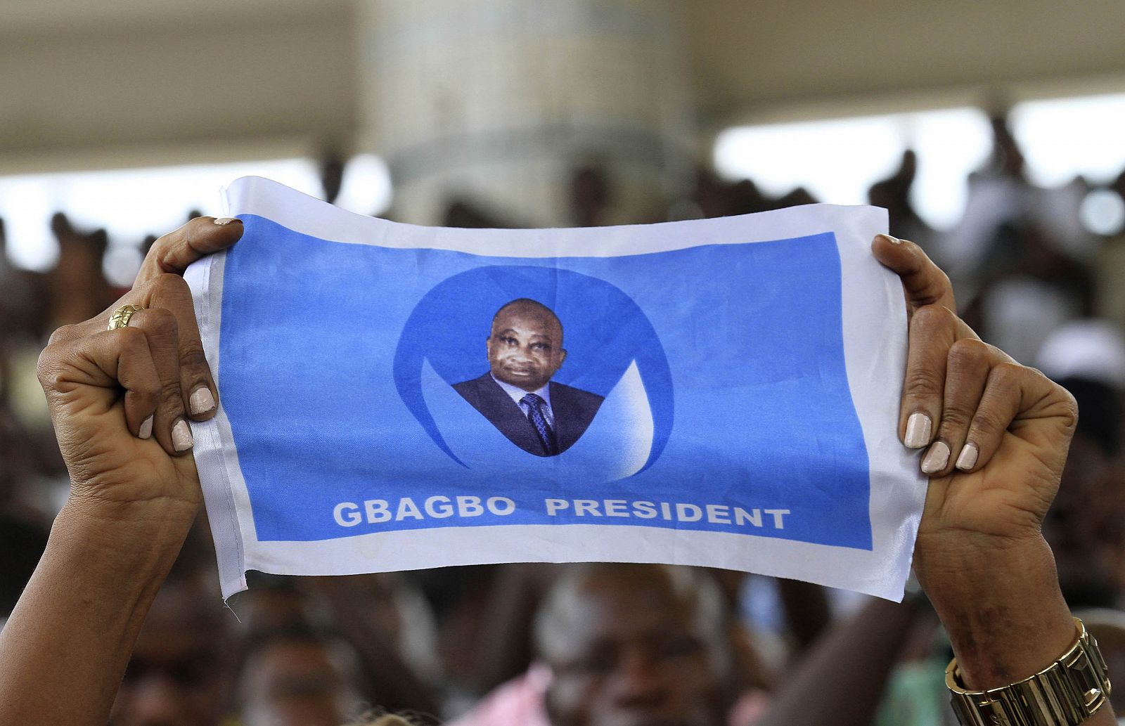 Un seguidor de Gbagbo muestra una bandera electoral con su rostro