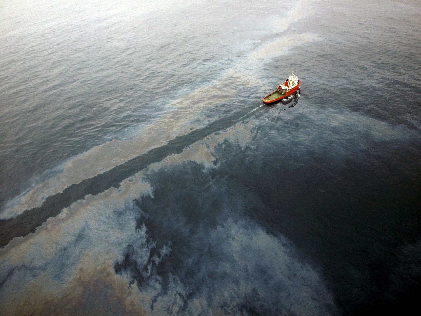 Fotografía facilitada por Salvamento Marítimo de uno de los barcos de la decena de los que están trabajando en la limpieza de la mancha.