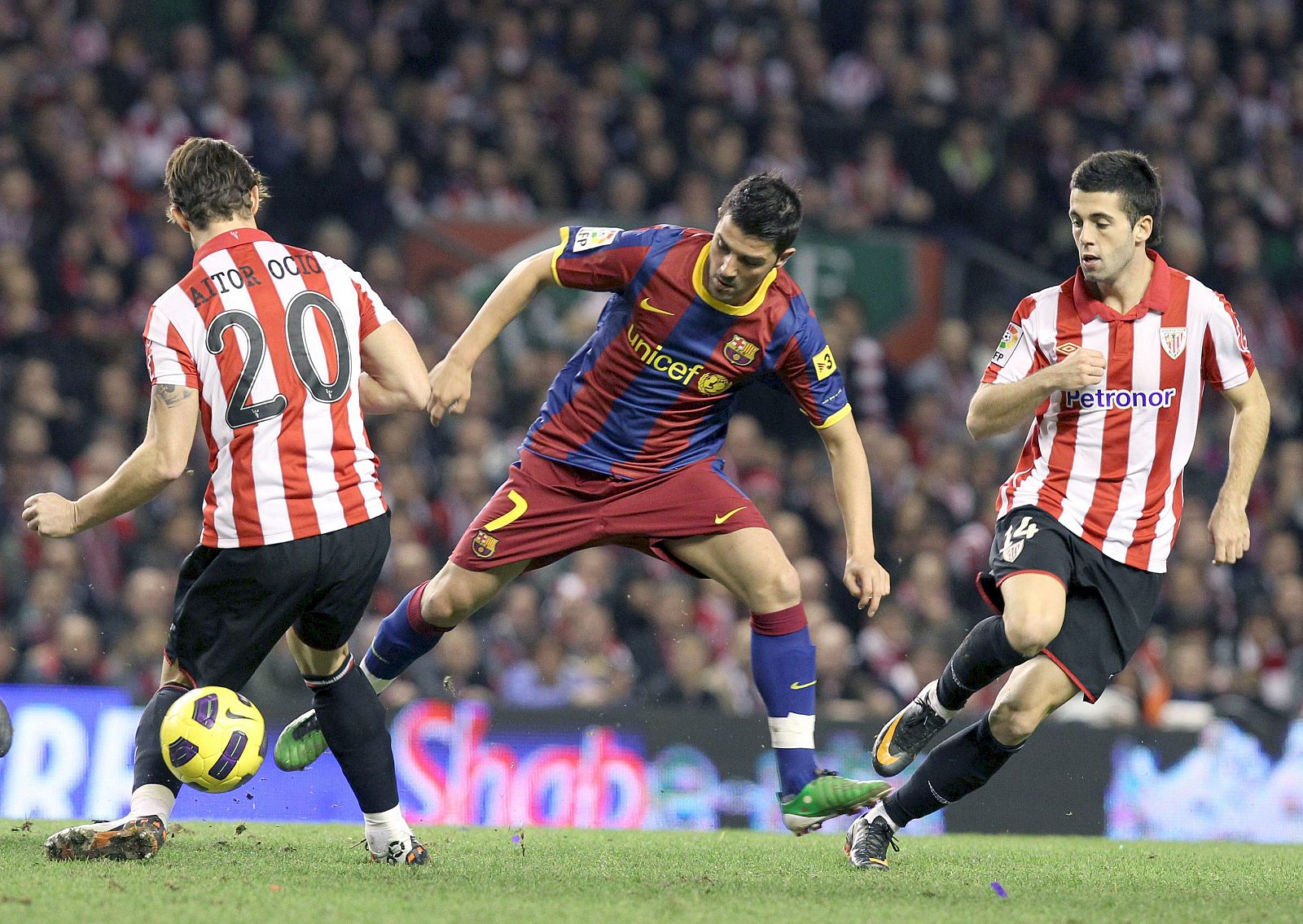 David Villa (c), intenta llevarse el balón ante los jugadores del Ath. de Bilbao, Aitor Ocio (i) y Ustariz.