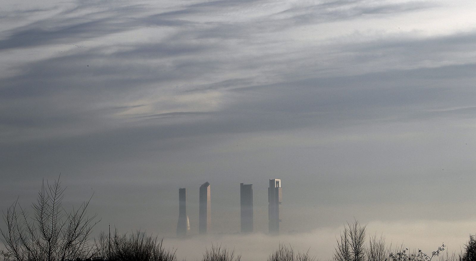 La niebla que cubre esta mañana parte de Madrid, y que ha obligado a cancelar vuelos en Barajas, se recorta contra las cuatro torres del paseo de la Castellana