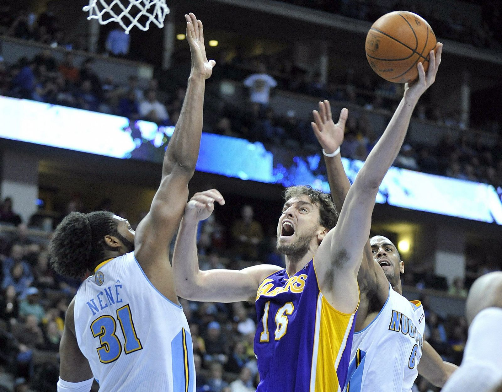 El pívot español de Los Ángeles Lakers, Pau Gasol, intenta encestar ante los jugadores de los Denver Nuggets.