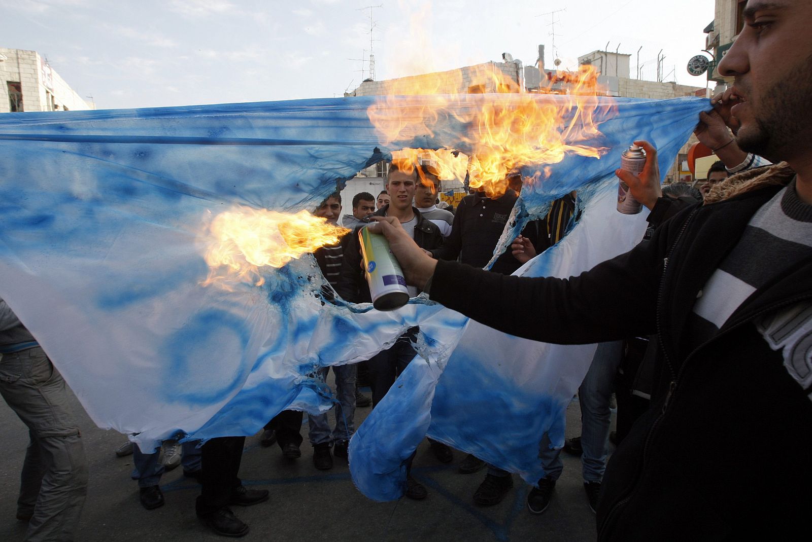 Palestinians burn a mock Israeli national flag with the word Al Jazeera during a protest in Ramallah